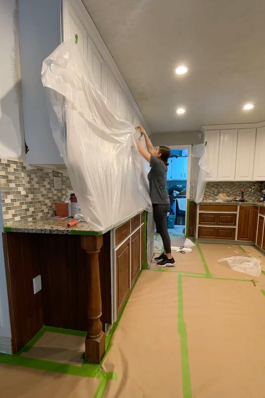 Masking a kitchen before painting with a paint sprayer and cabinet paint.